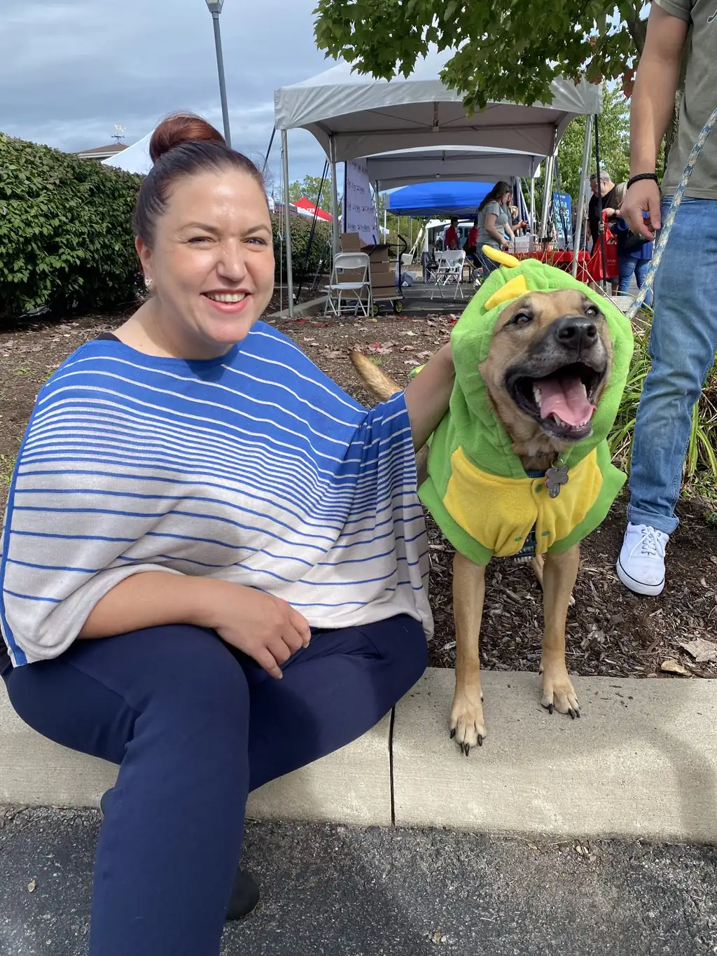 Jen Lunsford seated outdoors beside a dog in a costume